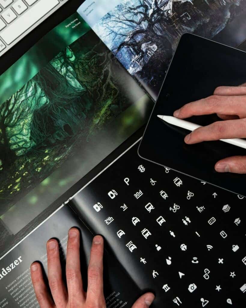 Open design portfolio spread beside an iPad and drawing pen, from a portfolio-focused UI/UX design program