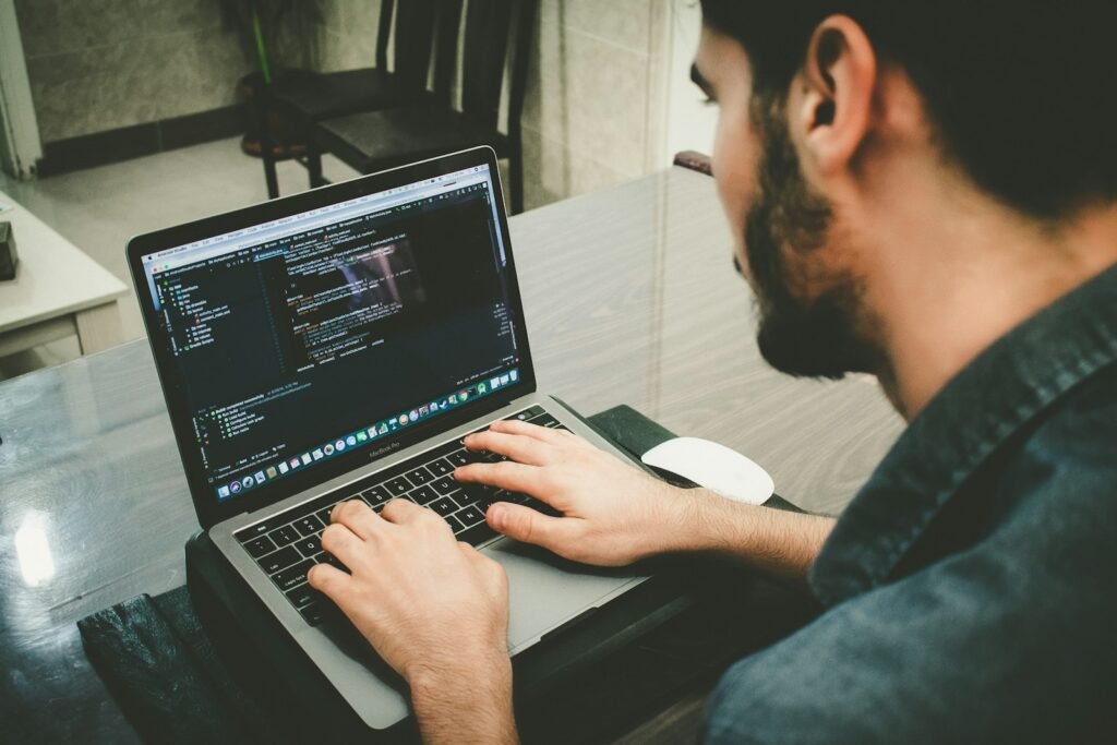 Designer writing code on a laptop while learning vibe coding