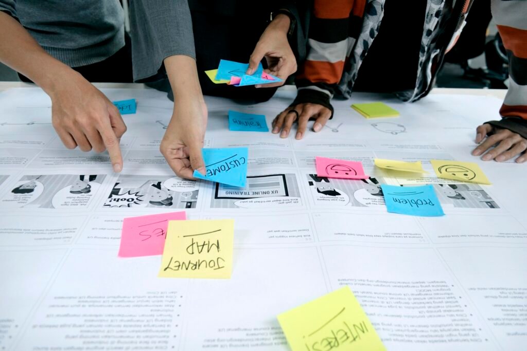 Career changers collaborating on sticky-note wireframes in a UI/UX design bootcamp workshop