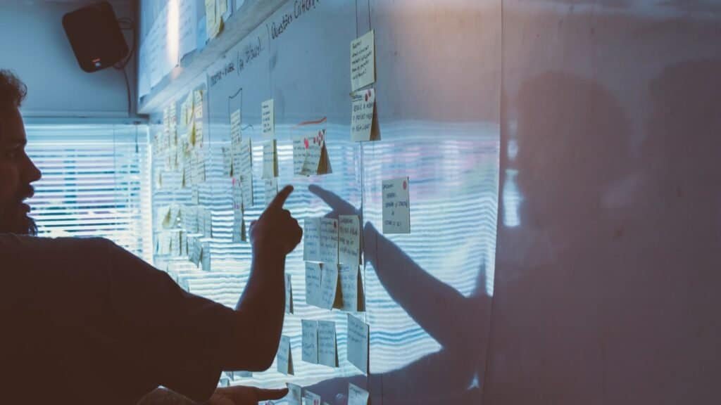 Instructor giving critique on design work pinned to a wall, illustrating how to choose a UX bootcamp by its instructors