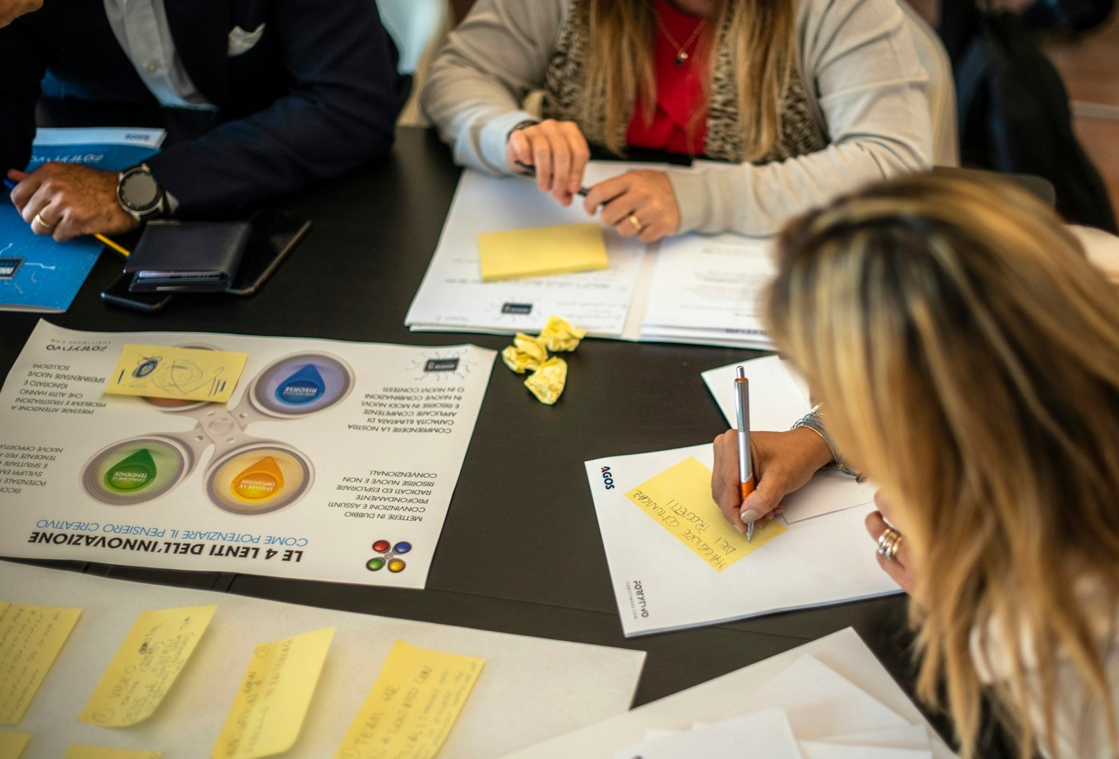 Designers reviewing portfolio case study pages together around a table in a portfolio school critique