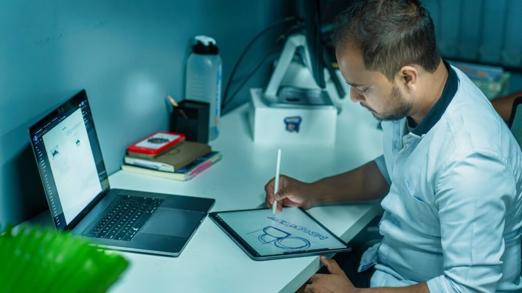 Designer working at a desk on a tablet, weighing whether UI/UX design bootcamps are worth the cost